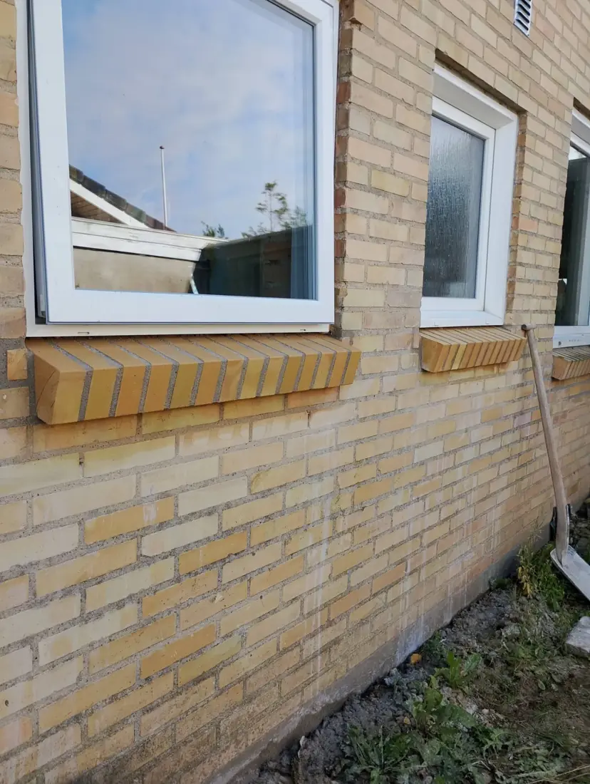 Ny sålbænk i gule mursten under et vindue