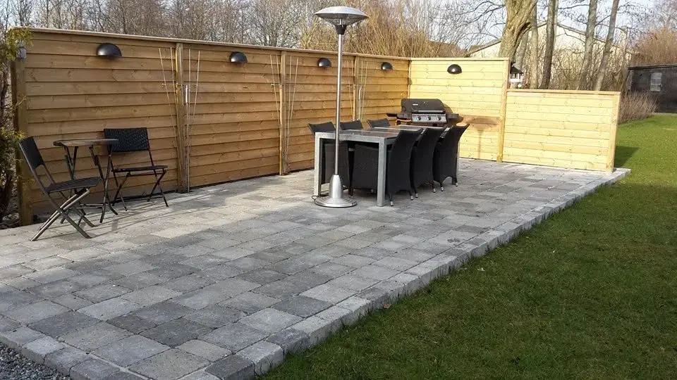 Terrasse med fliser foran et træhegn